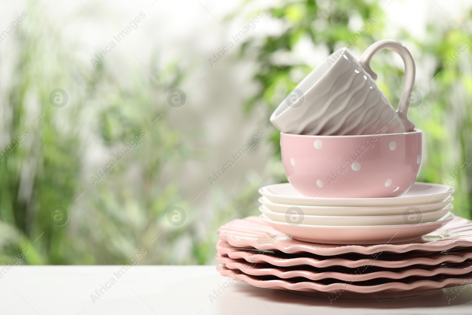 Photo of Beautiful ceramic dishware and cup on white table outdoors, space for text