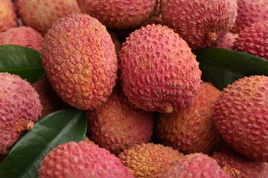 Pile of fresh ripe lychees with leaves as background, closeup