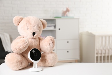 Baby camera with toy on table in room, space for text. Video nanny