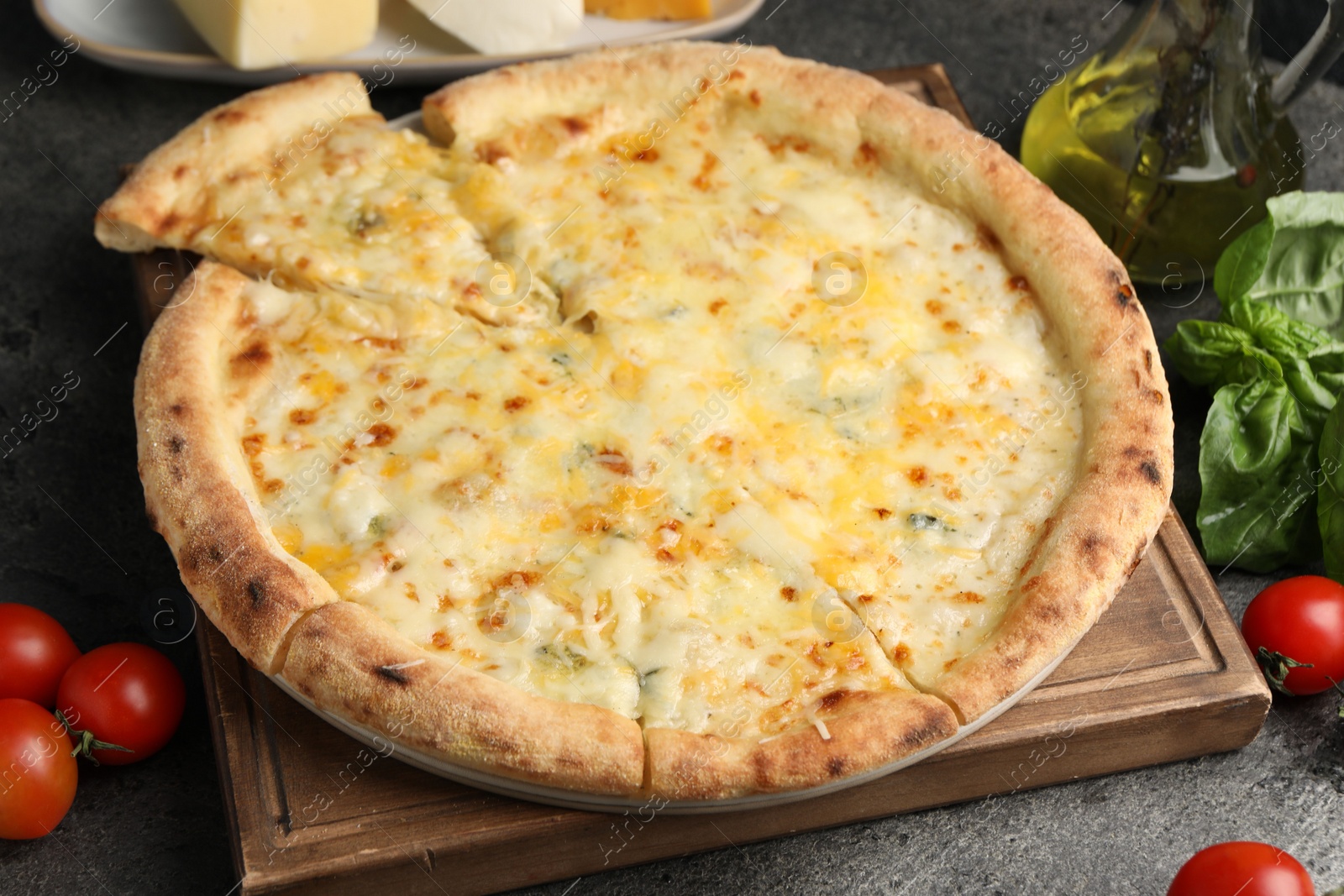 Photo of Delicious cheese pizza and ingredients on dark grey table