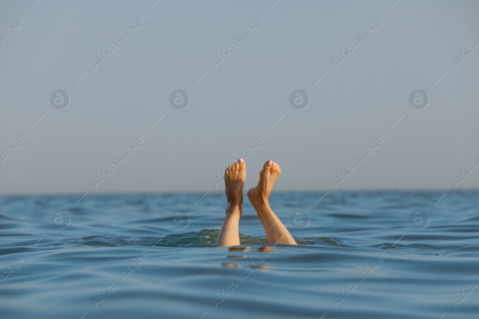 Photo of Drowning woman's legs sticking out of sea