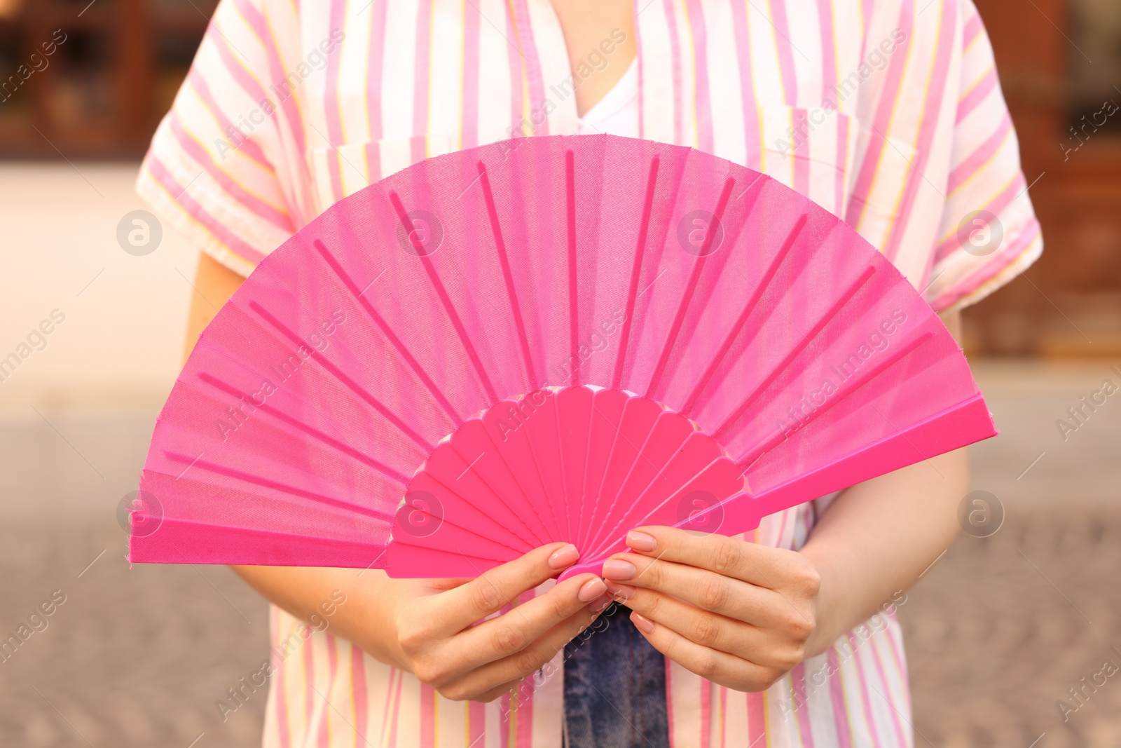 Photo of Woman with pink hand fan outdoors, closeup