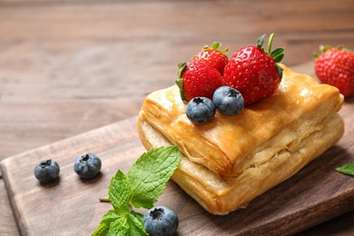 Photo of Fresh delicious puff pastry with sweet berries on wooden table, closeup. Space for text