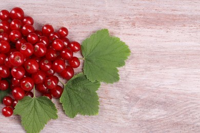 Ripe red currants on light wooden table, flat lay. Space for text