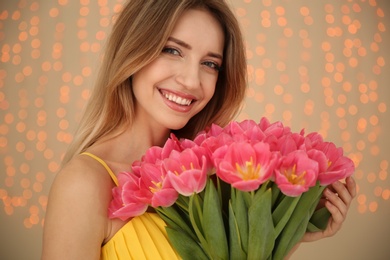 Photo of Portrait of smiling young girl with beautiful tulips on blurred background. International Women's Day