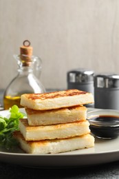 Photo of Delicious turnip cake with arugula and soy sauce on table, closeup