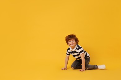 Photo of Happy little boy dancing on yellow background. Space for text