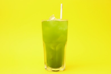 Glass of delicious iced green matcha tea on yellow background