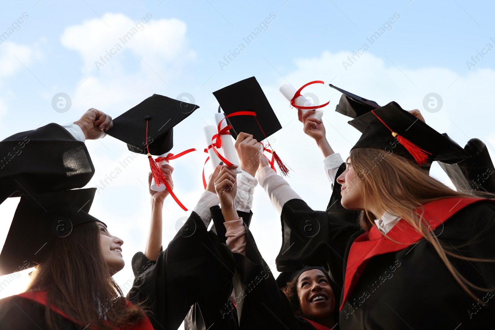 Photo of Group of students with diplomas outdoors. Graduation ceremony