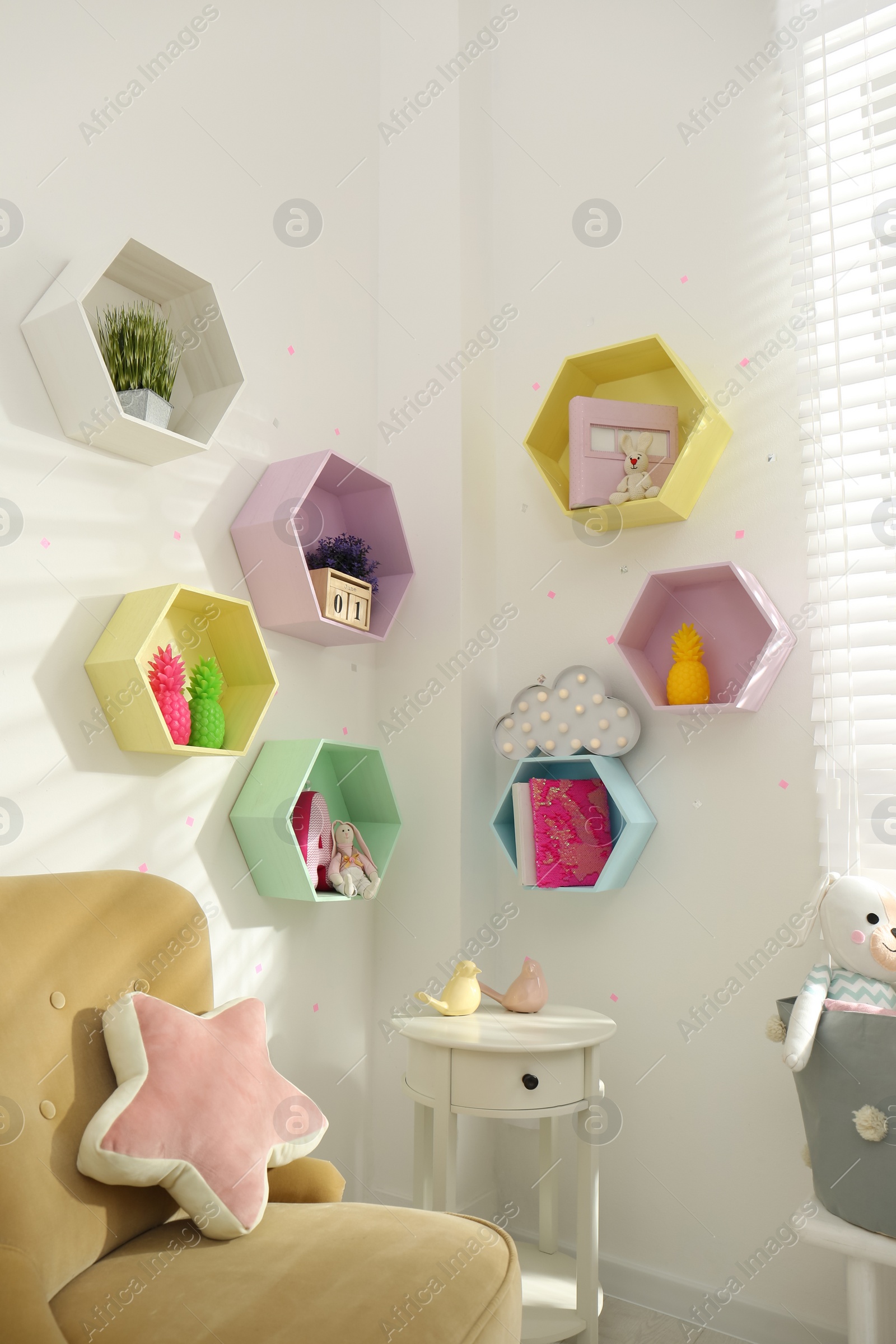 Photo of Hexagon shaped shelves on white wall in nursery. Interior design