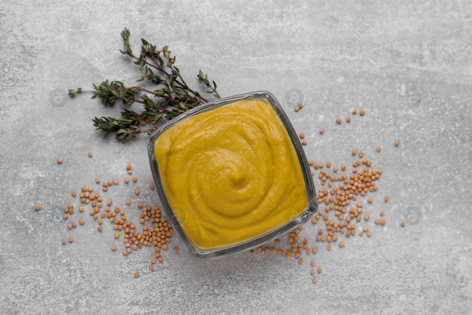 Photo of Delicious mustard, seeds and dry thyme on light grey table, flat lay