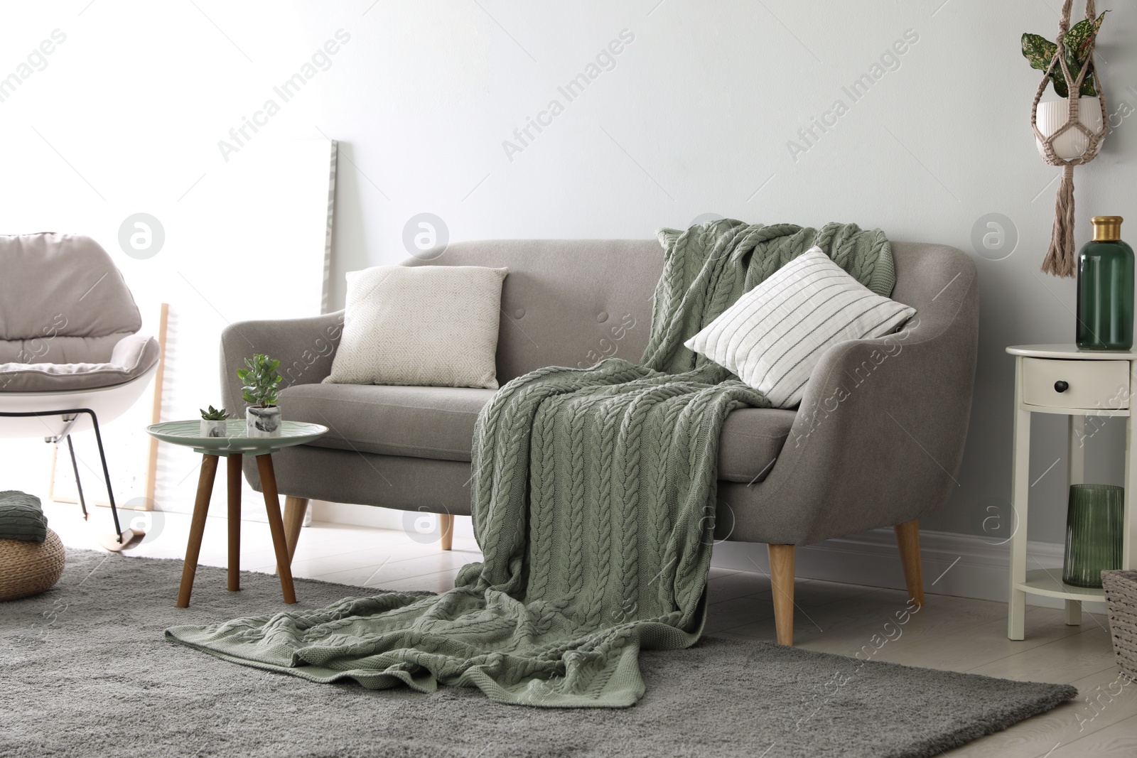 Photo of Soft knitted blanket on sofa in room. Home interior