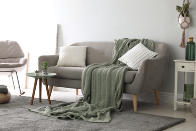 Soft knitted blanket on sofa in room. Home interior