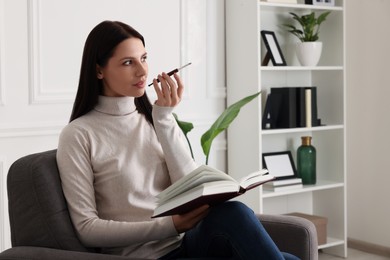 Woman using cigarette holder for smoking while reading book indoors