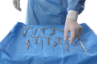 Photo of Doctor near table with surgical instruments on light background, closeup