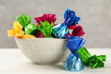 Photo of Candies in colorful wrappers on white wooden table, closeup