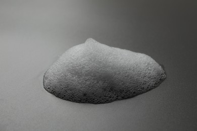 Drop of fluffy soap foam on grey background