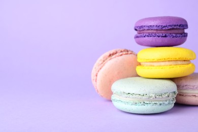 Photo of Delicious colorful macarons on violet background. Space for text