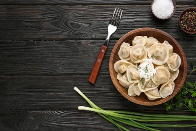 Photo of Flat lay composition with tasty dumplings on black wooden table, space for text