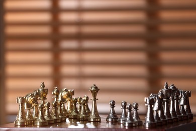 Photo of Chessboard with game pieces near window indoors, space for text