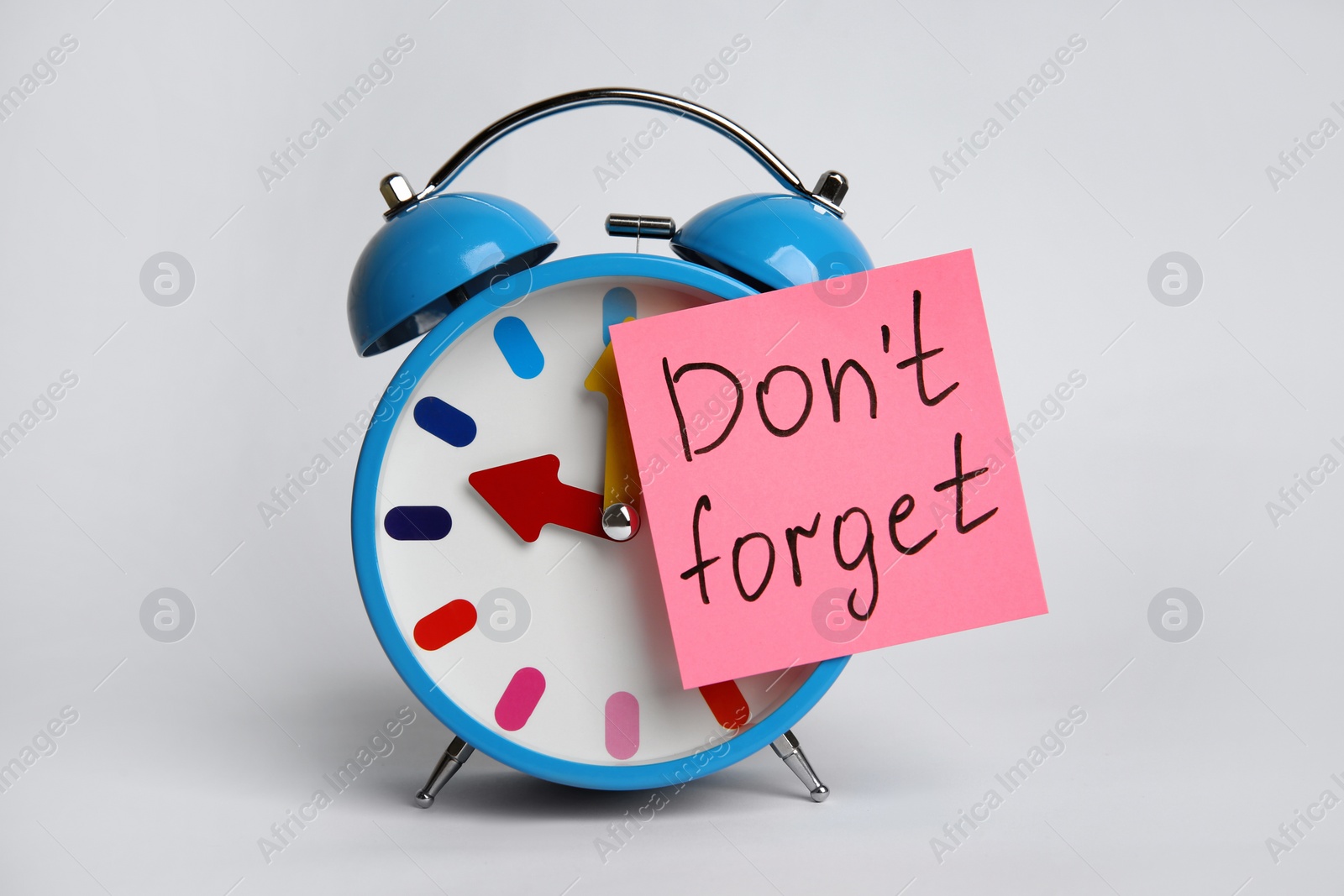 Photo of Alarm clock and reminder note with text Don't forget on light grey background