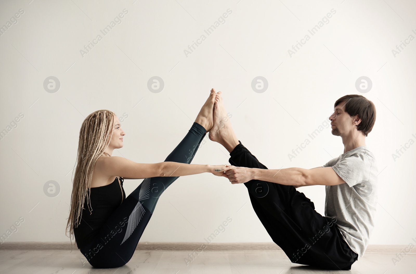 Photo of Young man and woman practicing yoga indoors