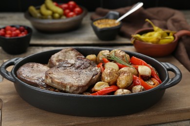 Tasty beef tongue pieces with potatoes, pepper and rosemary on wooden board, closeup