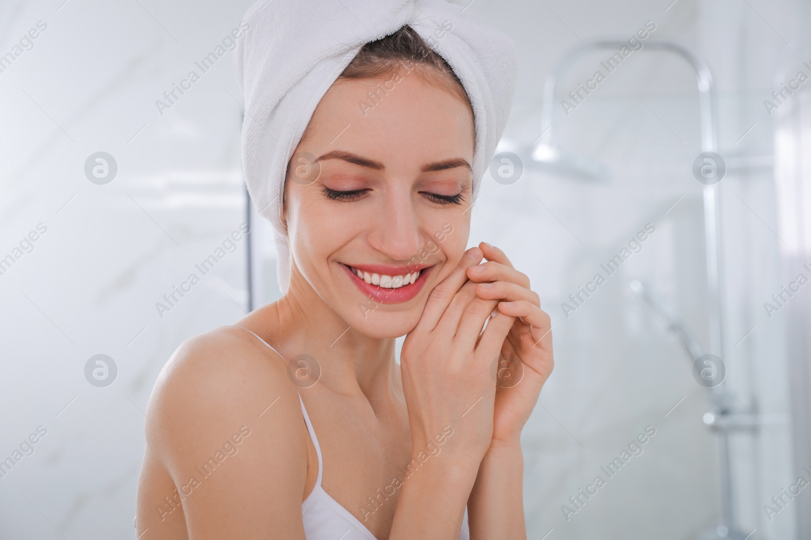 Photo of Beautiful young woman with hair wrapped in towel after washing at home