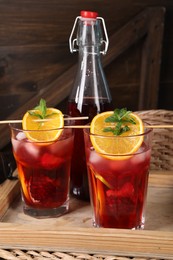 Bottle and glasses of delicious refreshing sangria on wooden tray
