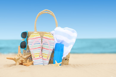 Bag and beach objects on sand near sea, space for text