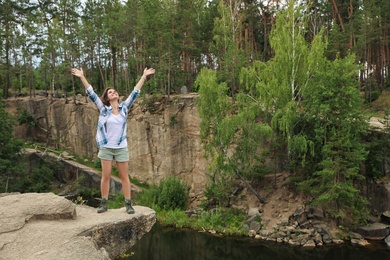 Photo of Young woman on rocky mountain near lake. Camping season