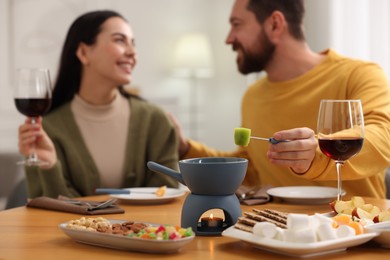 Photo of Affectionate couple enjoying fondue during romantic date indoors, selective focus