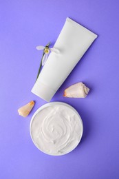 Photo of Jar and tube of cream, seashells with snowdrop flower on violet background, flat lay