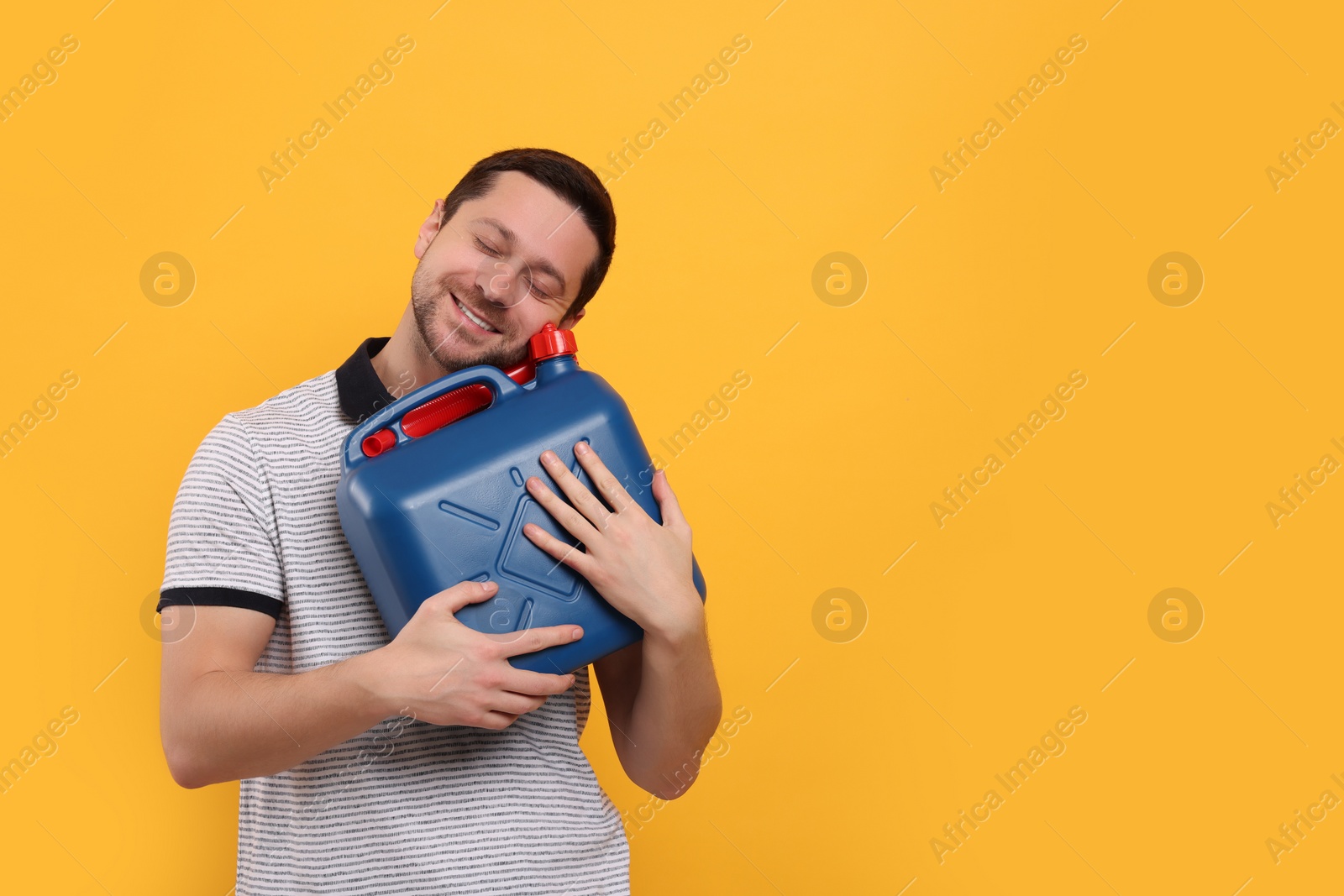 Photo of Man holding blue canister on orange background. Space for text