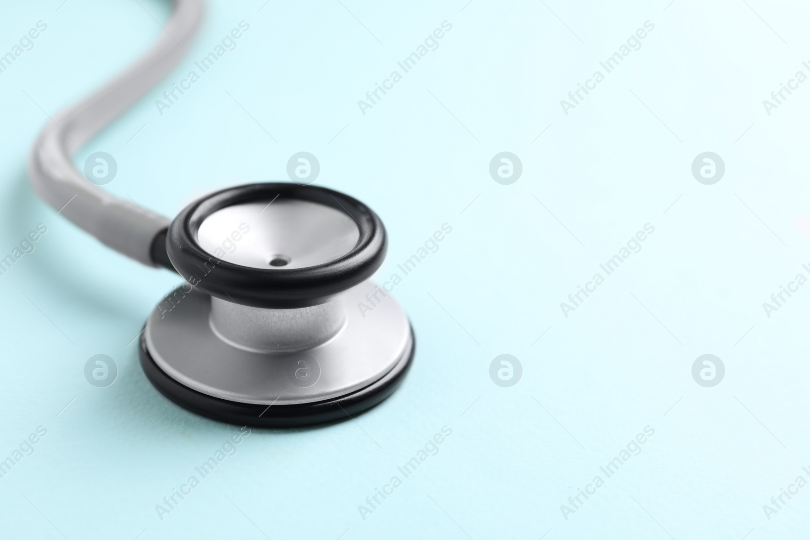Photo of Stethoscope on light blue background, closeup. Space for text