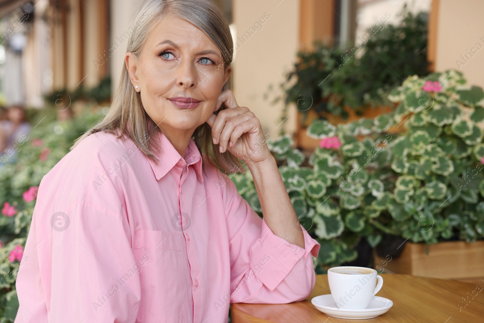 Photo of Portrait of beautiful senior woman with cup of coffee at table in outdoor cafe