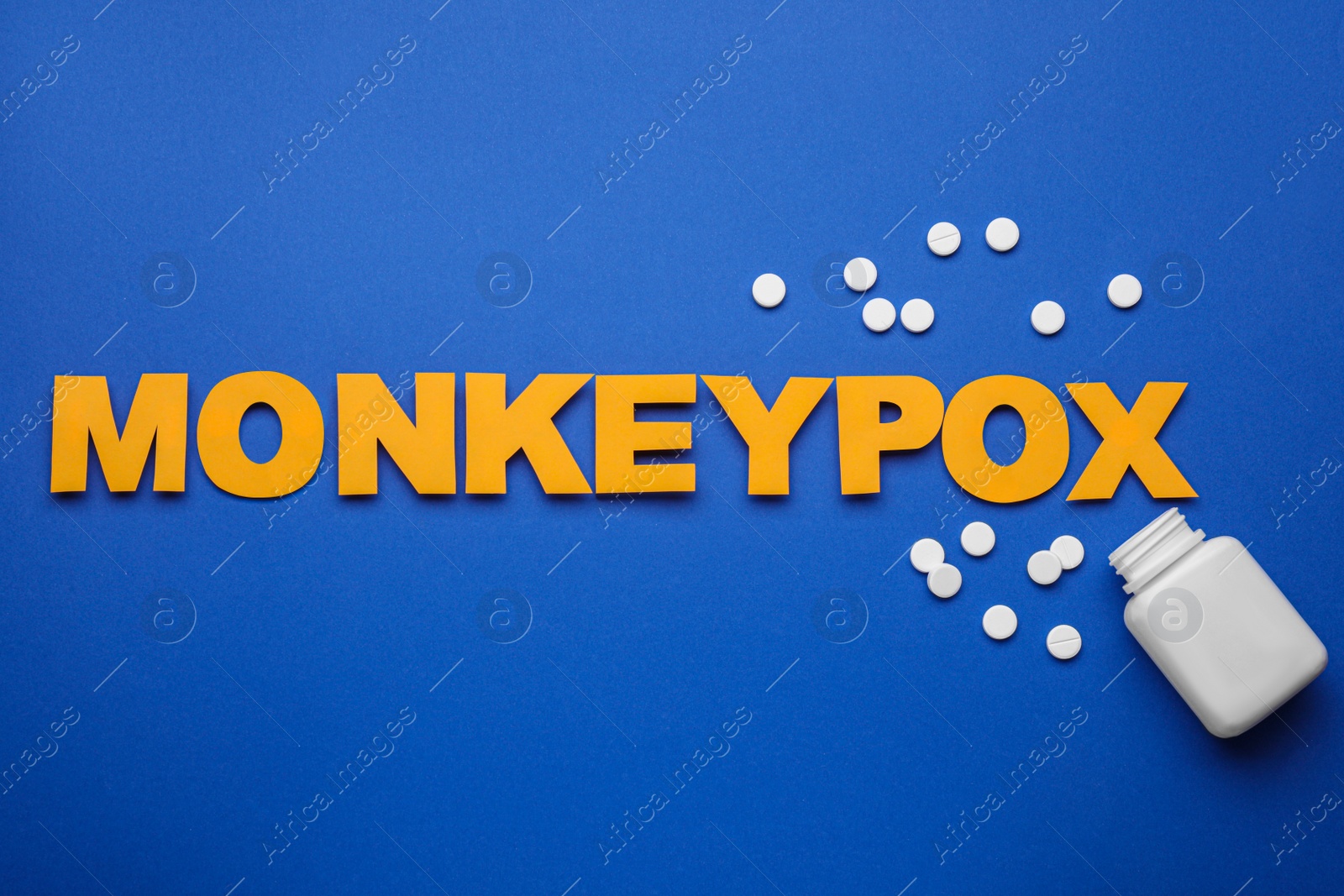 Photo of Word Monkeypox, bottle and pills on blue background, flat lay
