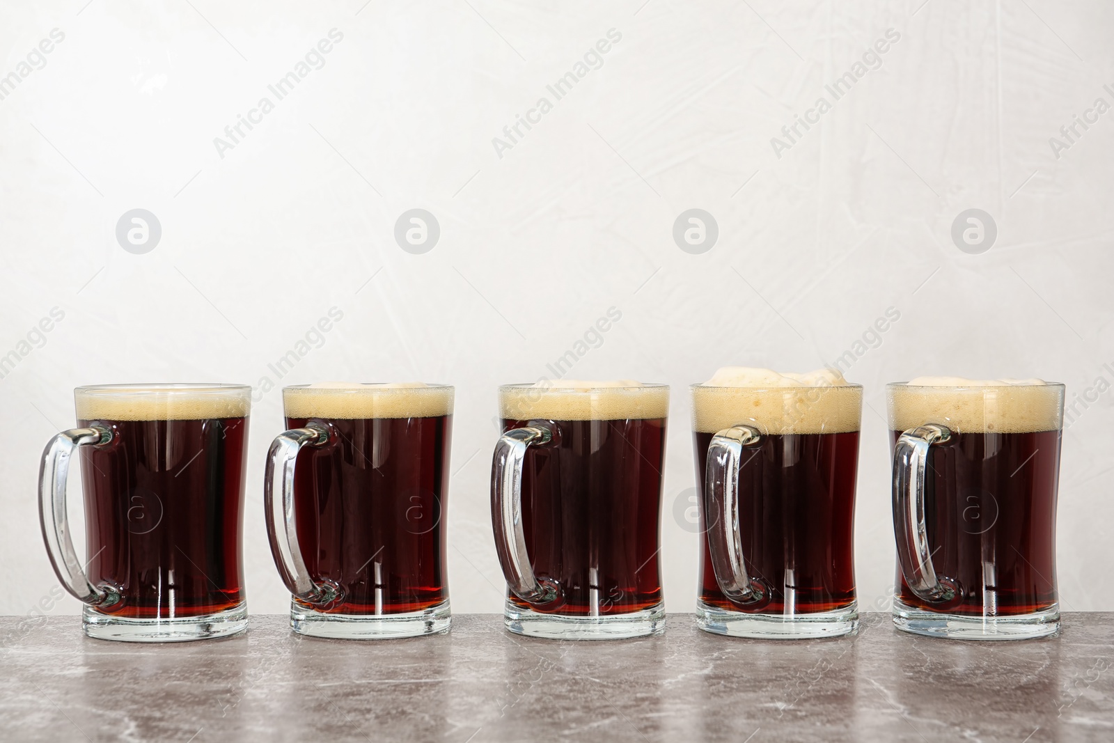 Photo of Row of glass mugs with beer on table