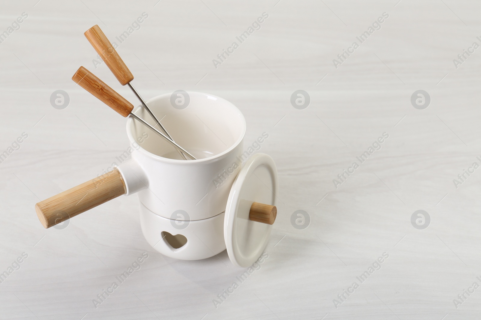 Photo of Fondue set on white wooden table, space for text