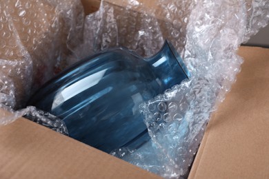 Photo of Beautiful glass vase in box with bubble wrap, closeup