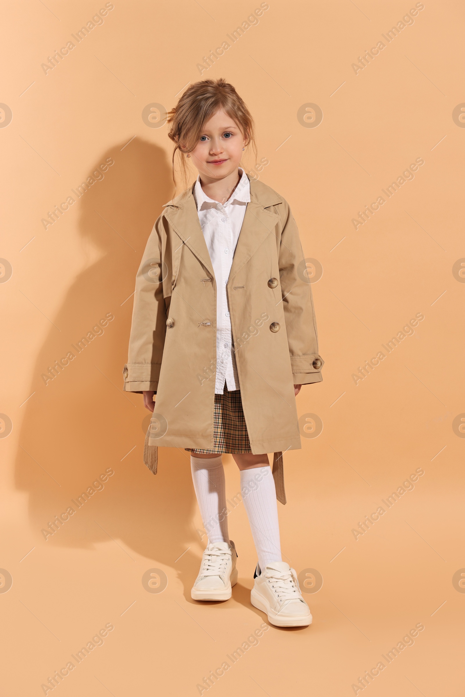 Photo of Fashion concept. Stylish girl posing on pale orange background