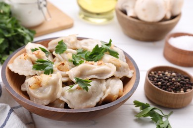 Photo of Delicious dumplings (varenyky) with potatoes, onion and parsley served on white wooden table