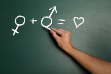 Sex Education. Woman drawing male gender sign in equation on green chalkboard, closeup. Man plus woman equals love