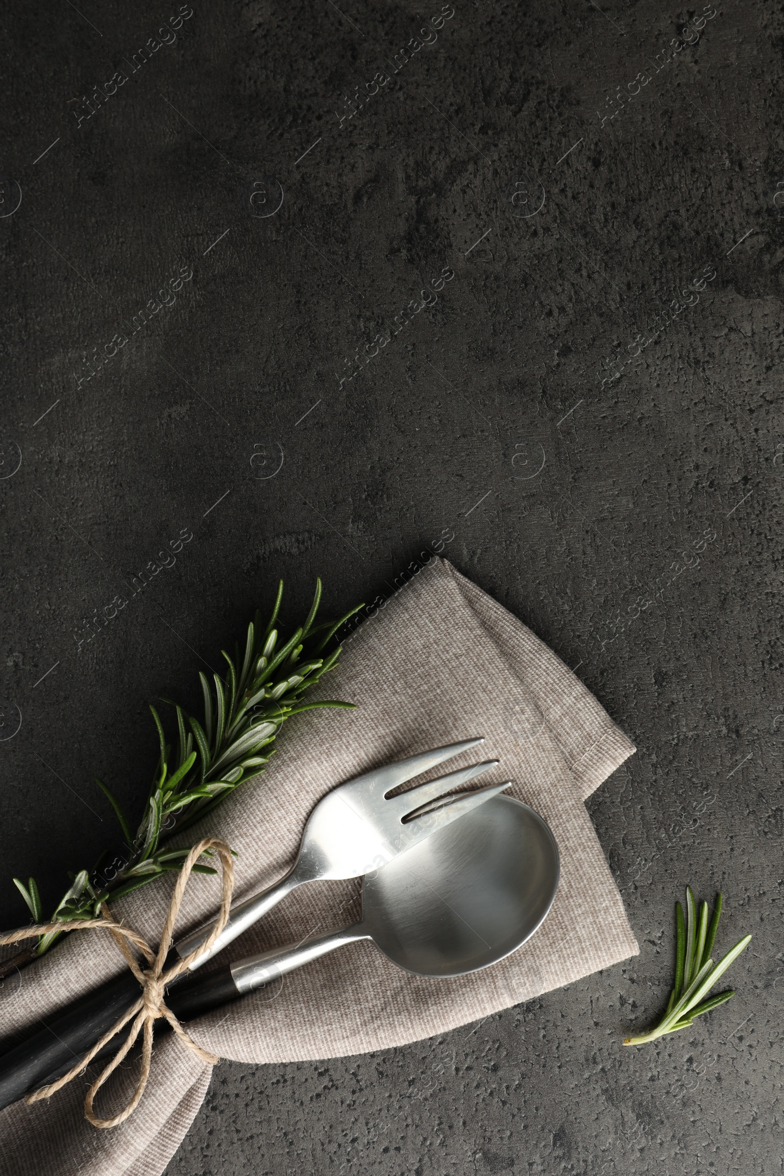 Photo of Stylish setting with cutlery and napkin on black table, top view. Space for text