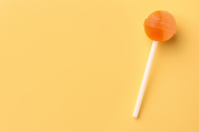 One tasty lollipop on yellow background, top view. Space for text