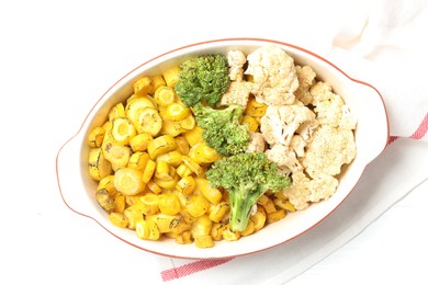 Baked yellow carrot with broccoli and cauliflowers in baking dish on white table, top view