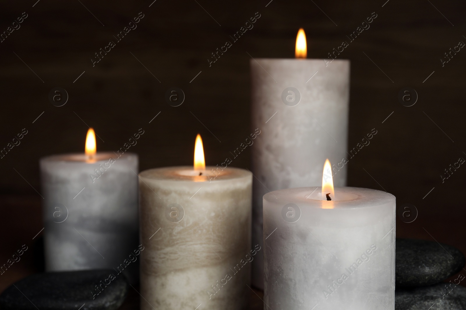 Photo of Burning candles and spa stones on dark background