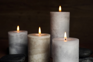 Photo of Burning candles and spa stones on dark background