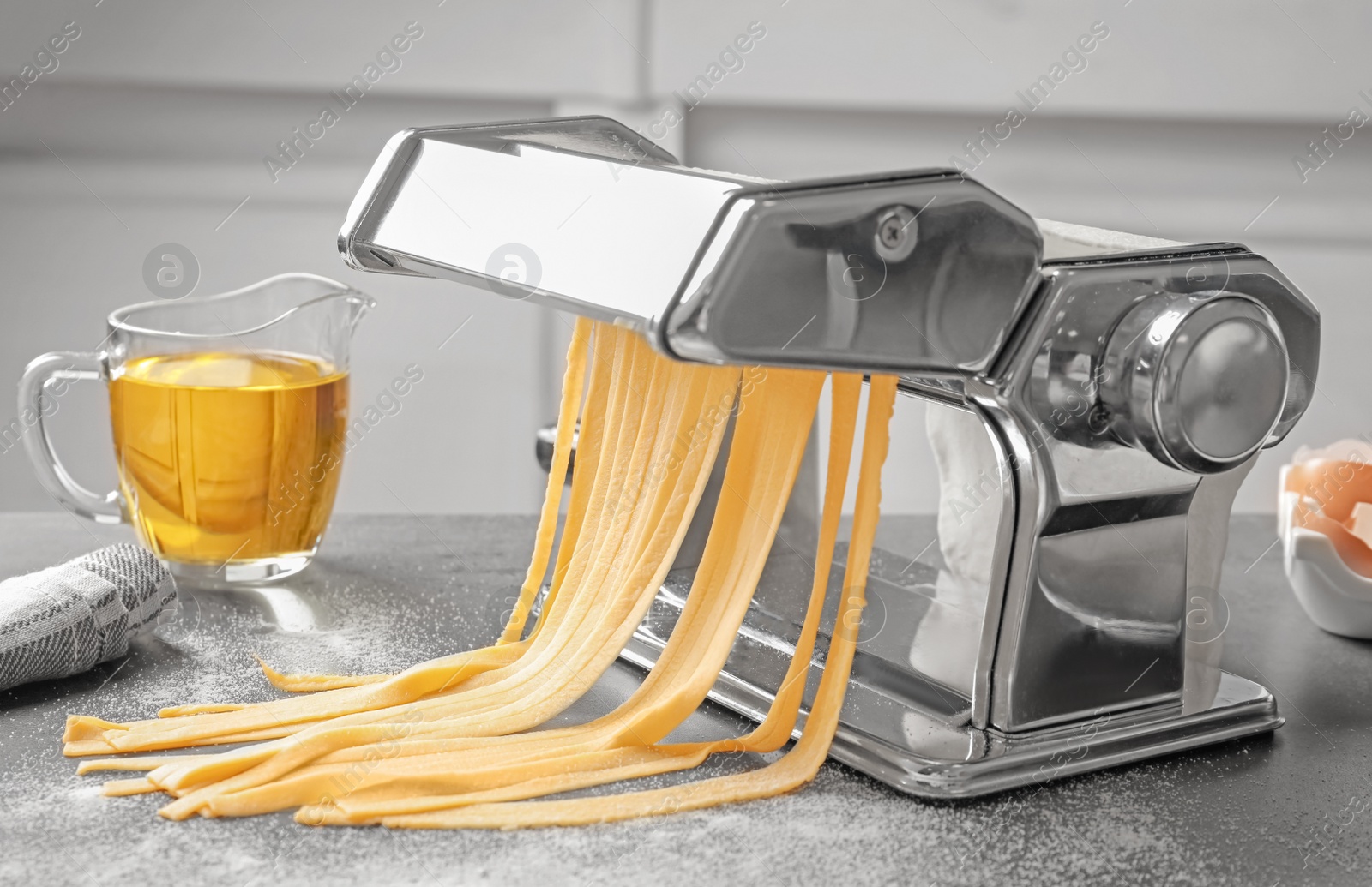 Photo of Pasta maker with dough and oil on kitchen table