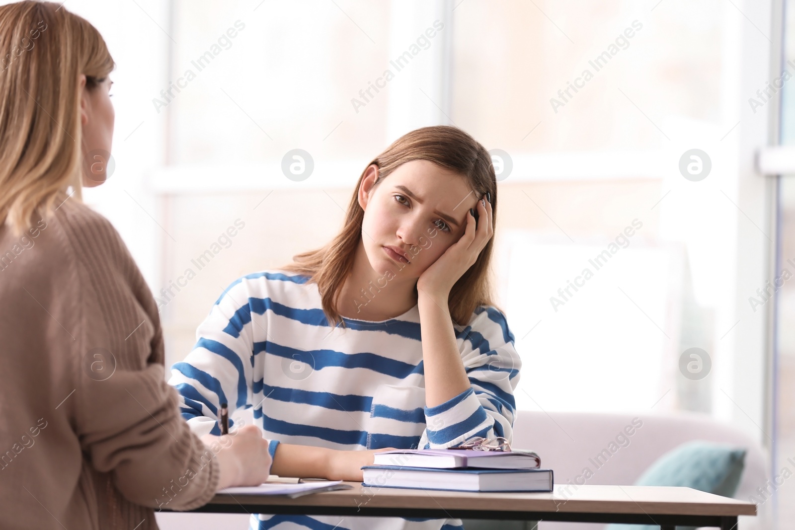 Photo of Young female psychologist working with teenage girl in office